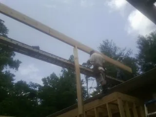 Carpenter setting a ridge beam over a new addition frame — Ice Dam Removal by Roofing Brothers in Frazee