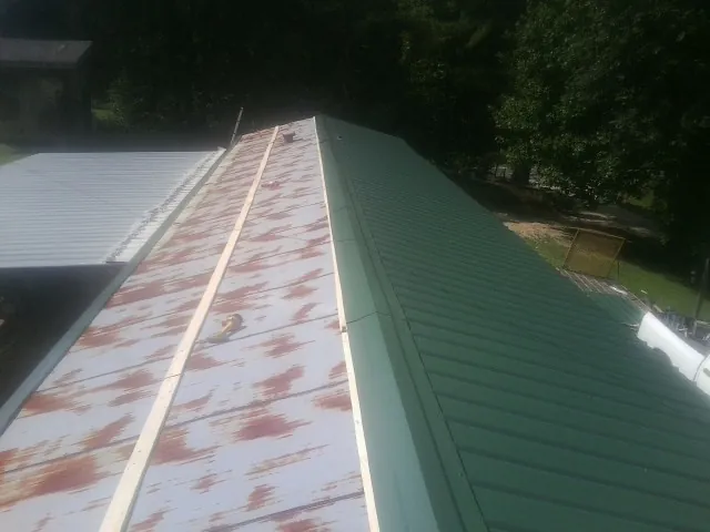 Old rusted panels beside newly installed green metal roofing — Wind Damage Roof Repair by Roofing Brothers in Frazee