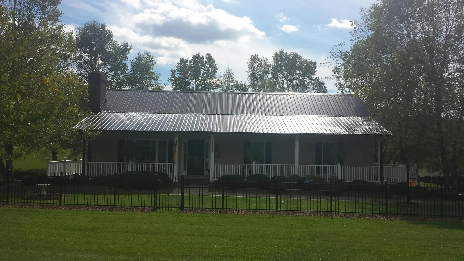 Gray metal roof on a brick ranch with a full width front porch — Gutter Guard Installation work by our crew in Frazee